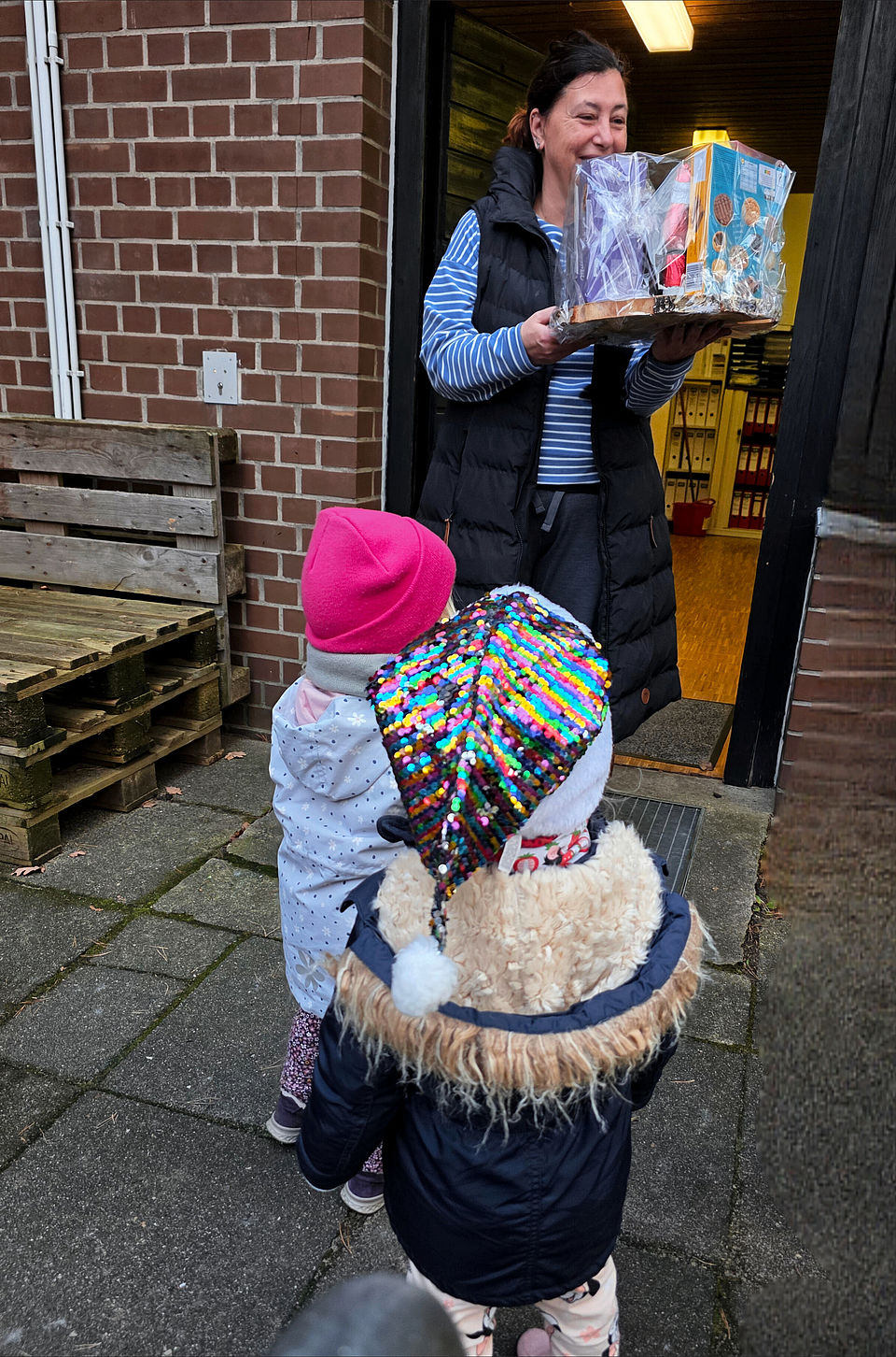 Doreen Wagner, Leiterin der DRK Bereitschaft, steht mit zwei Kindern zusammen und erhält die von ihnen gebastelten Weihnachtsgeschenke.