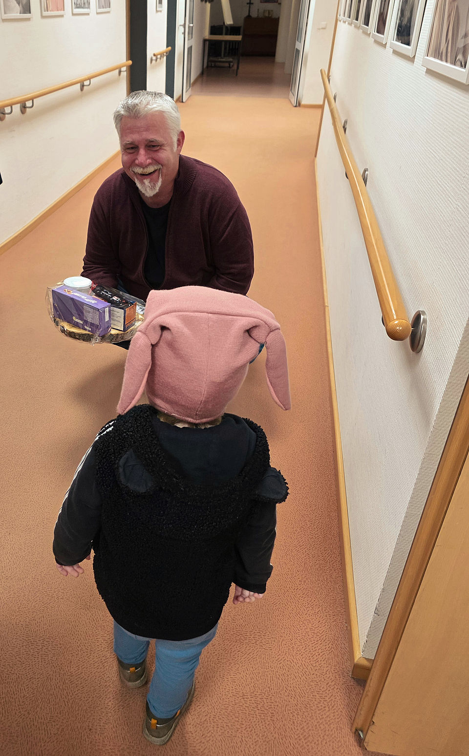 Marc Friedrich, Leiter des DRK Altenpflegeheims, steht mit Kindern der Kindertagesstätte Osterberg zusammen und nimmt ihre gebastelten Weihnachtsgeschenke entgegen.