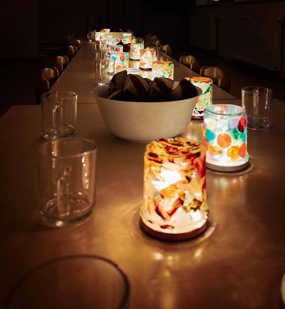 Tisch mit bunt gestalteten Lichtergläsern